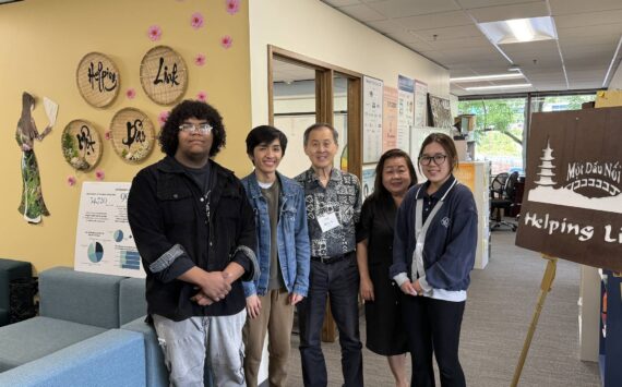 Executive Director Minh-Duc Nguyen (center right) and Ron Choi (center) rely on the work of volunteers to keep Helping Link running. Photo by Drew Dotson/Renton Reporter